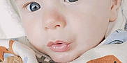 Loïs a rejoint le concours — aidez-le/la à gagner de superbes lots ! baby, infant, face, blue_eyes, blanket, patterned_cloth, close_up, curious, soft_skin, biscuit, mouth, lips, hair, child, cute, portrait, indoors, young, wrapped, expression