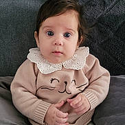 Lucia a rejoint le concours — aidez-le/la à gagner de superbes lots ! baby, infant, child, sweater, lace_collar, cat_face, couch, gray_couch, plush, seated, curious_expression, wide_eyes, hands, knitted_clothing, indoors, portrait, cute, soft_lighting, comfortable, cozy