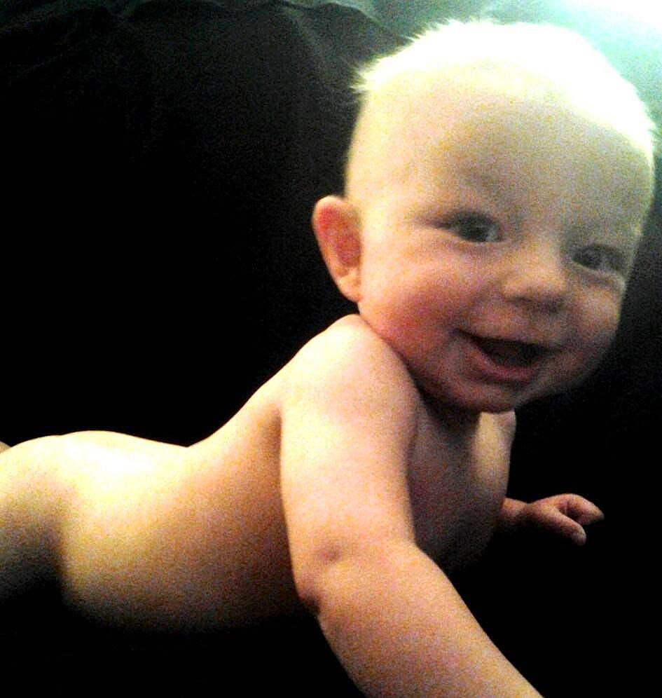 Stewart is registered to the contest to win money with this photo: arm, baby, cheek, chest, child, elbow, eye, flash_photography, flesh, flooring, gesture, happy, human_leg, lip, person, portrait_photography, sitting, smile, thumb, toddler