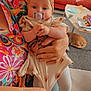 Ava-Melody is registered to the contest to win money with this photo: baby, pacifier, headband, adult_hand, dress, tights, living_room, sofa, coffee_table, cat, floor, colorful_clothing, person, indoor, furniture, hand, home, child, cute, seated