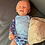 baby, infant, smiling, blue_clothing, whale_pattern, seagull_pattern, blanket, couch, leather, happy, lying_down, cute, child, one_person, indoor, skin, head, face, hand, leg