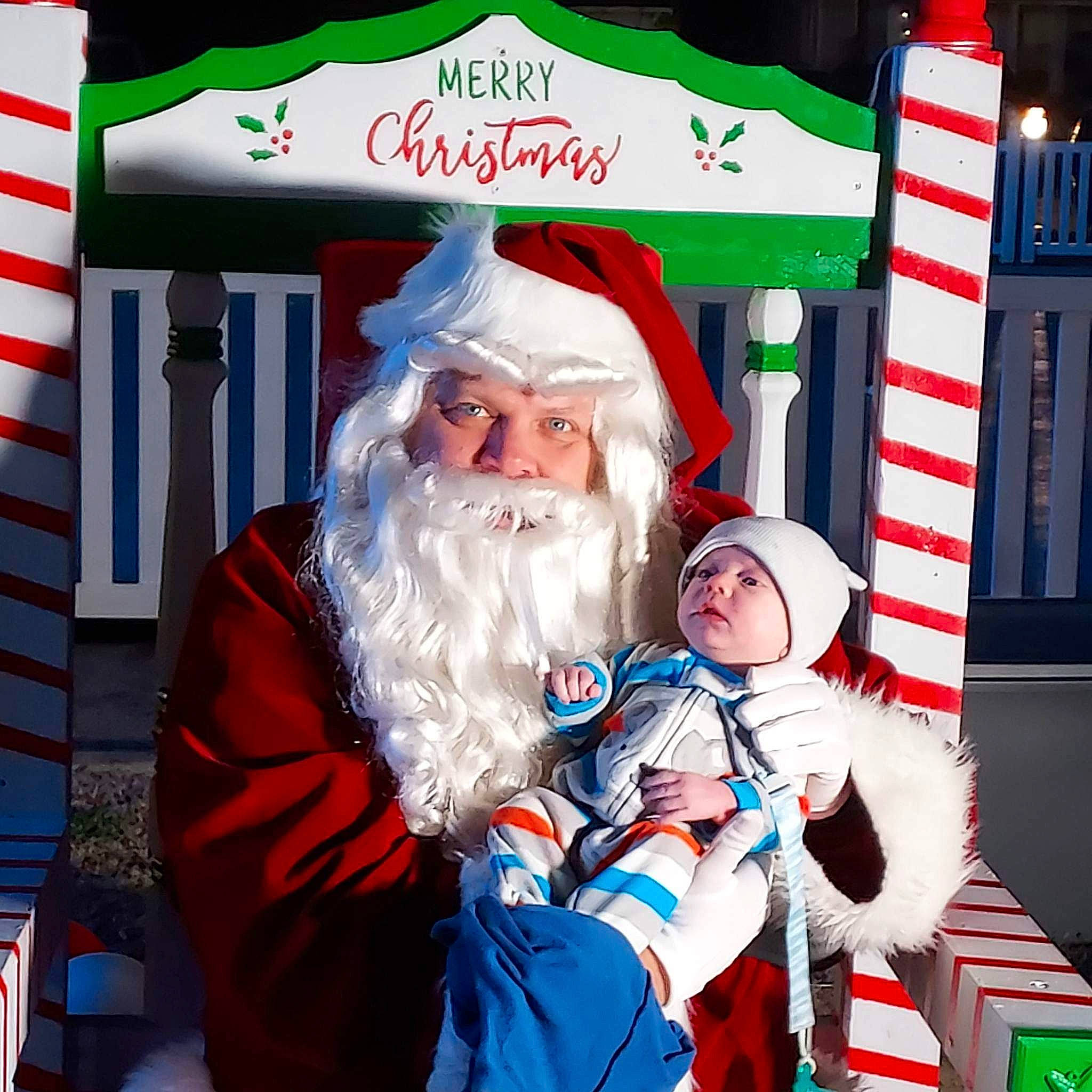 Izaak is registered to the contest to win money with this photo: beard, christmas, christmas_decoration, christmas_eve, costume_hat, event, face, facial_hair, fictional_character, fun, green, happy, hat, headwear, holiday, interior_design, lap, moustache, person, pleased