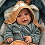 baby, infant, smiling, hood, blanket, cushion, blue_clothing, face, hand, cute, cozy, seat, child, soft_texture, indoor, portrait, happy, young_child, closeup, warm