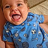 baby, child, infant, smiling, happy, blue_clothing, onesie, sports_pattern, indoor, carpet, blanket, portrait, cute, young_child, person, head, face, cheerful, closeup, sitting