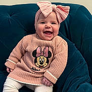 Nelliel participe au concours pour gagner de l'argent avec cette photo : baby, child, smiling, headband, pink, bow, sweater, minnie_mouse, knitwear, seated, indoor, couch, happy, cute, person, toddler, clothing, portrait, furniture, cozy