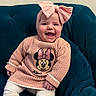 baby, child, smiling, headband, pink, bow, sweater, minnie_mouse, knitwear, seated, indoor, couch, happy, cute, person, toddler, clothing, portrait, furniture, cozy