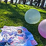 baby, blanket, balloon, grass, trees, quilt, outdoor, sunlight, nature, child, peaceful, park, relaxing, colorful, pastel, lying_down, soft_texture, shade, scenic, infant