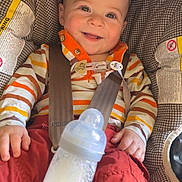 Basile a rejoint le concours — aidez-le/la à gagner de superbes lots ! baby, bottle, car_seat, child, clothing, cute, eyes, face, hand, happy, head, indoors, infant, milk, mouth, red_pants, seatbelt, sitting, smiling, striped_shirt