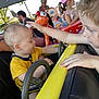 Basile participe au concours pour gagner de l'argent avec cette photo : amusement_park, carnival, child, colorful, curly_hair, daylight, face_paint, family, fun, interaction, outdoor, patting, people, playful, ride, seat, steering_wheel, toddler, toy, yellow_shirt