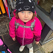 Winry a rejoint le concours — aidez-le/la à gagner de superbes lots ! backpack_straps, beanie, child, cold_weather, curious_expression, curly_hair, green_eyes, looking_up, outdoor, pavement, person, pink_jacket, raincoat, rainy_day, standing, street, umbrella, urban, wet_pavement, white_shoes
