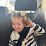 car_interior, car_seat, child, child_safety, curly_hair, cute, girl, hairbands, happy, indoor, pink_watch, portrait, seat_headrest, seatbelt, sitting, smile, striped_cardigan, toy, white_flower, young