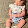 baby, infant, child, bib, mamas_boy, white_booties, striped_clothing, sitting, couch, beige, curious, face, hands, legs, indoor, portrait, cute, soft_light, expression, young