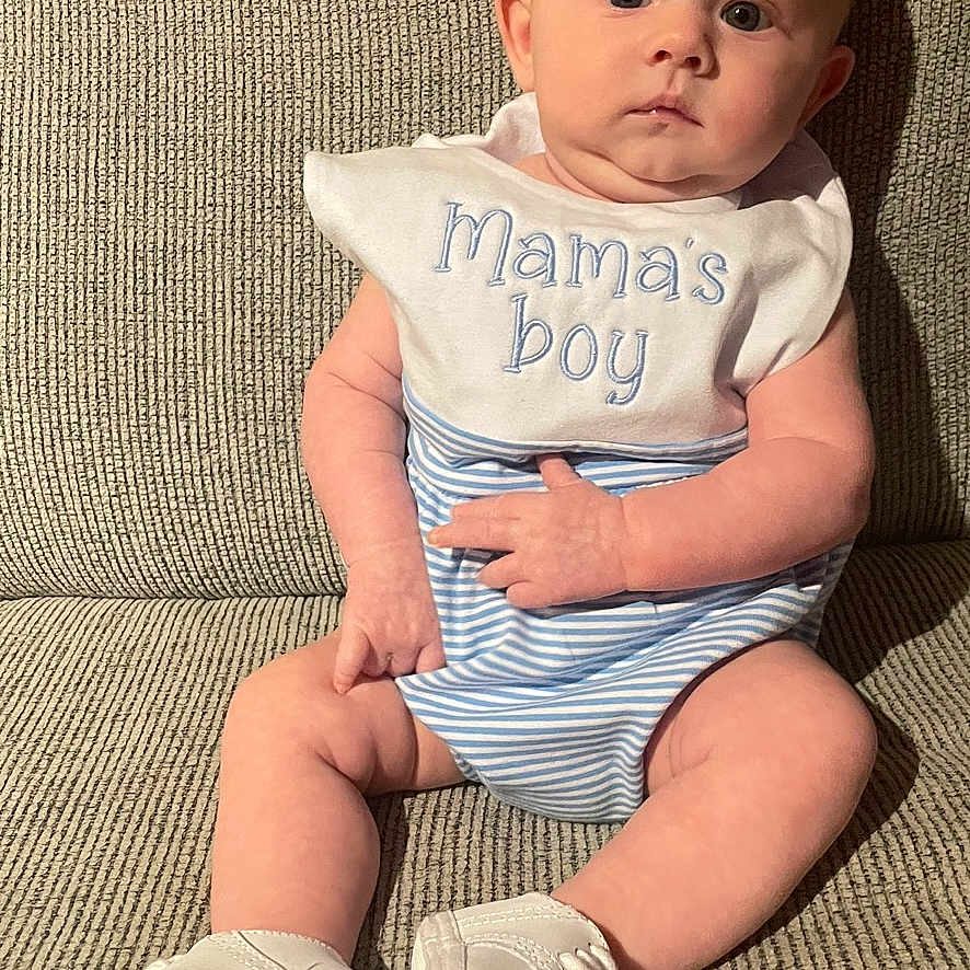 Kohen Raine joined the competition — help win amazing prizes! baby, beige, bib, child, couch, curious, cute, expression, face, hands, indoor, infant, legs, mamas_boy, portrait, sitting, soft_light, striped_clothing, white_booties, young