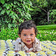 Maverick is registered to the contest to win money with this photo: baby, blanket, child, crochet, cute, daylight, eyes, face, grass, greenery, hands, happy, infant, nature, outdoor, person, portrait, shirt, smile, young