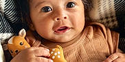 Maverick joined the competition — help win amazing prizes! baby, blanket, brown_clothing, child, closeup, cozy, curly_hair, cute, deer, face, hand, happy, indoor, infant, looking_up, portrait, resting, small_toy, soft_texture, toy