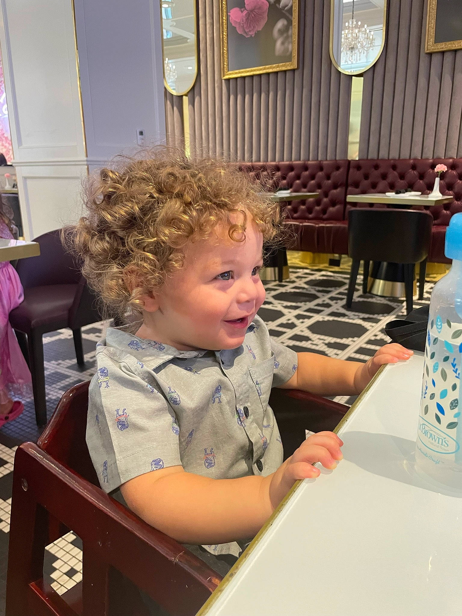 Kamdyn is registered to the contest to win money with this photo: chair, child, curtain, desk, event, fun, furniture, leisure, person, plastic_bottle, play, room, sitting, smile, t_shirt, table, toddler, vacation, water_bottle, wood