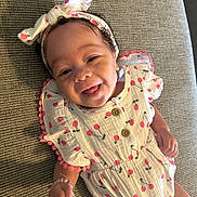 Phoenix joined the competition — help win amazing prizes! baby, child, smiling, headband, bow, cherry_pattern, clothing, cute, happy, infant, lying_down, fabric, texture, hand, bracelet, portrait, playful, indoors, person, skin