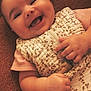 baby, smile, happy, infant, face, hand, clothing, sleep_sack, textile, pattern, pink_shirt, lying_down, closeup, skin, cute, cheerful, indoors, fabric, soft, portrait