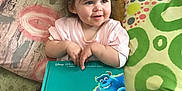 Brooklyn joined the competition — help win amazing prizes! book, casual, child, colorful, couch, hair_accessories, happy, home, indoor, monsters_inc, pigtails, pillow, pink_shirt, playful, reading, seated, smile, storybook, toddler, young_child