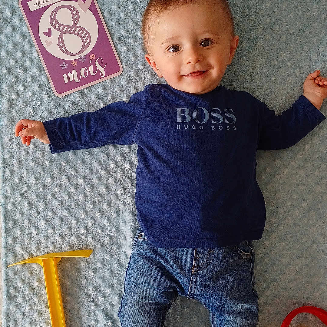 Ange participe au concours pour gagner de l'argent avec cette photo : baby, blue_blanket, child, cute, floor, gold_shoes, hugo_boss, indoor, infant, jeans, long_sleeve_shirt, lying_down, milestone_card, playtime, purple_card, red_shoes, smiling, sneakers, toy_bucket, yellow_toy