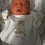 newborn, baby, infant, sleepy, bib, bear, blanket, stars, moon, pattern, white_clothing, cute, cozy, portrait, child, soft_light, indoor, face, small_hands, peaceful