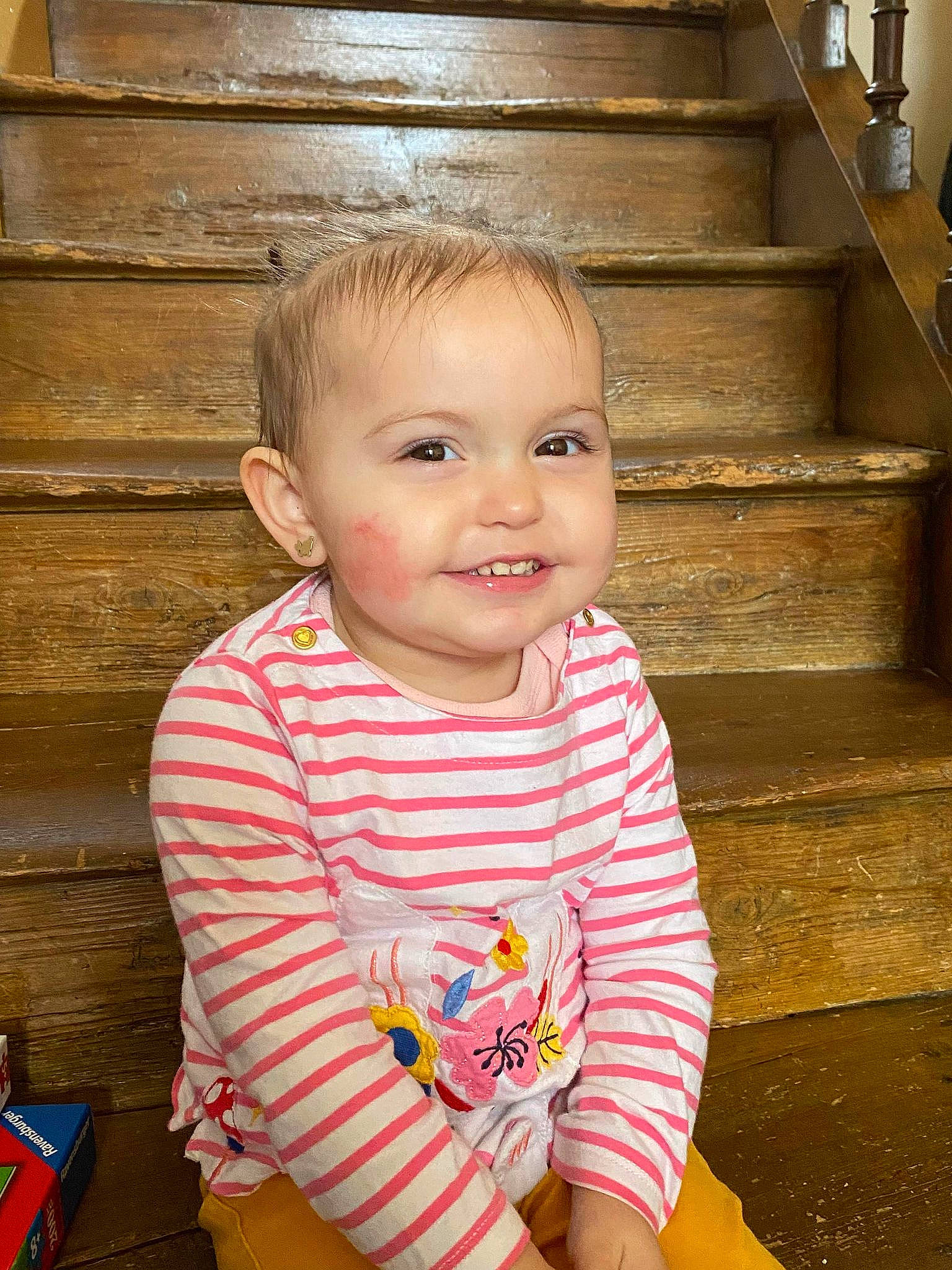 Aloïse participe au concours pour gagner de l'argent avec cette photo : baby, baby_toddler_clothing, beauty, cheek, child, chin, fun, happy, hardwood, iris, joy, nose, person, sitting, skin, sleeve, smile, stairs, standing, t_shirt