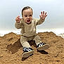 toddler, child, sand, beige_clothing, sneakers, happy, smiling, sitting, indoor, playful, person, portrait, cute, infant, hands_up, studio, light_background, young_child, casual_wear, footwear