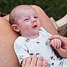 Justin joined the competition — help win amazing prizes! baby, infant, onesie, holding_hands, adult, lap, outdoor, grass, cute, expression, skin, person, child, newborn, small_hands, white_clothing, animal_print, relaxing, portrait, comfort