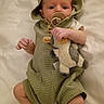 baby, infant, pacifier, plush_toy, green_clothing, hooded_romper, blanket, bed, cute, child, newborn, lying_down, soft_toys, indoors, small_hands, small_feet, sleepwear, portrait, adorable, resting
