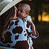 baby, woman, cowboy_hat, cow_print, outdoor, nature, forest, portrait, affection, holding, child, love, evening, soft_light, blurred_background, casual_clothing, head, face, person, warmth