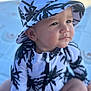 toddler, child, baby, hat, bucket_hat, clothing, pattern, palm_tree, outdoor, beach, blanket, sitting, portrait, cute, face, skin, expression, sunlight, summer, nature