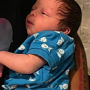 Azae is registered to the contest to win money with this photo: baby, infant, blue_clothing, fish_pattern, tattoo, arm, skin, face, person, sleepy, closeup, indoor, newborn, cute, child, holding, human, portrait, soft_light, casual