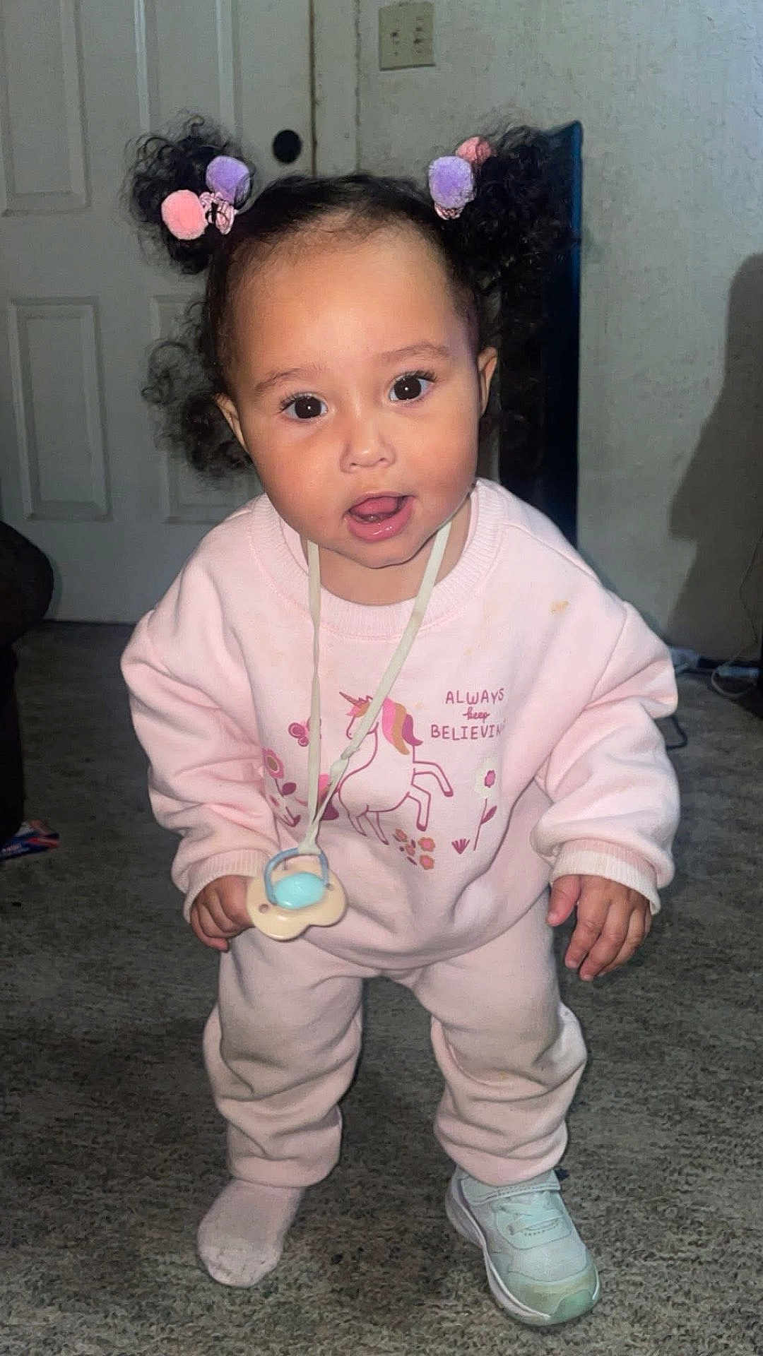 Halo joined the competition — help win amazing prizes! toddler, child, pink_clothing, pigtails, pacifier, unicorn_print, indoor, carpet, sneaker, sock, cute, curious, person, smiling, hair_accessory, baby, young_child, standing, floor, playful