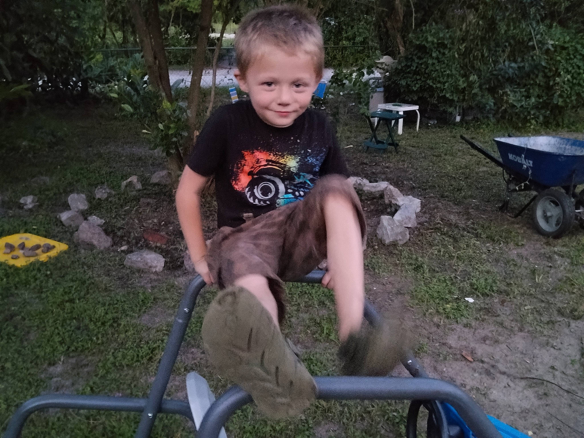 Braxton is registered to the contest to win money with this photo: cart, chair, fun, grass, joy, lap, lawn, leisure, outdoor_furniture, person, plant, recreation, shorts, sitting, smile, soil, t_shirt, tire, toddler, tree