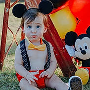Cash joined the competition — help win amazing prizes! toddler, child, mickey_mouse, balloons, outdoor, grass, toy, costume, headwear, bow_tie, red_shorts, suspenders, black_ears, plush_toy, pouting, sitting, sunlight, playful, cute, portrait
