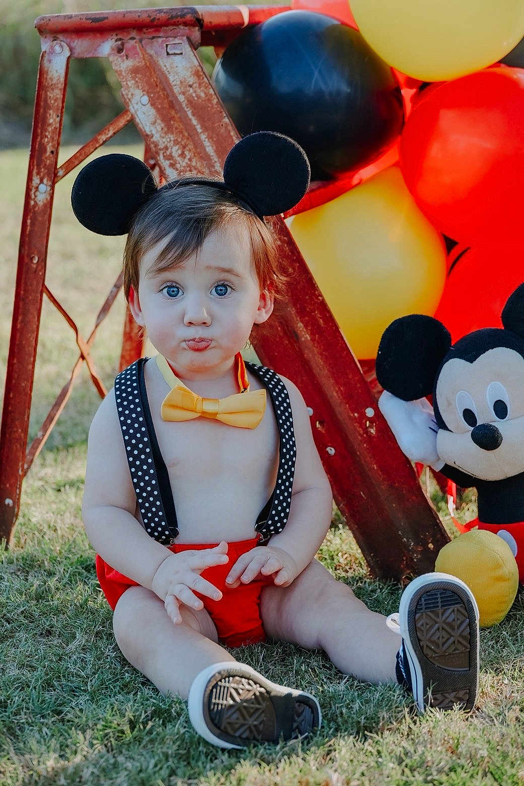 Cash joined the competition — help win amazing prizes! toddler, child, mickey_mouse, balloons, outdoor, grass, toy, costume, headwear, bow_tie, red_shorts, suspenders, black_ears, plush_toy, pouting, sitting, sunlight, playful, cute, portrait