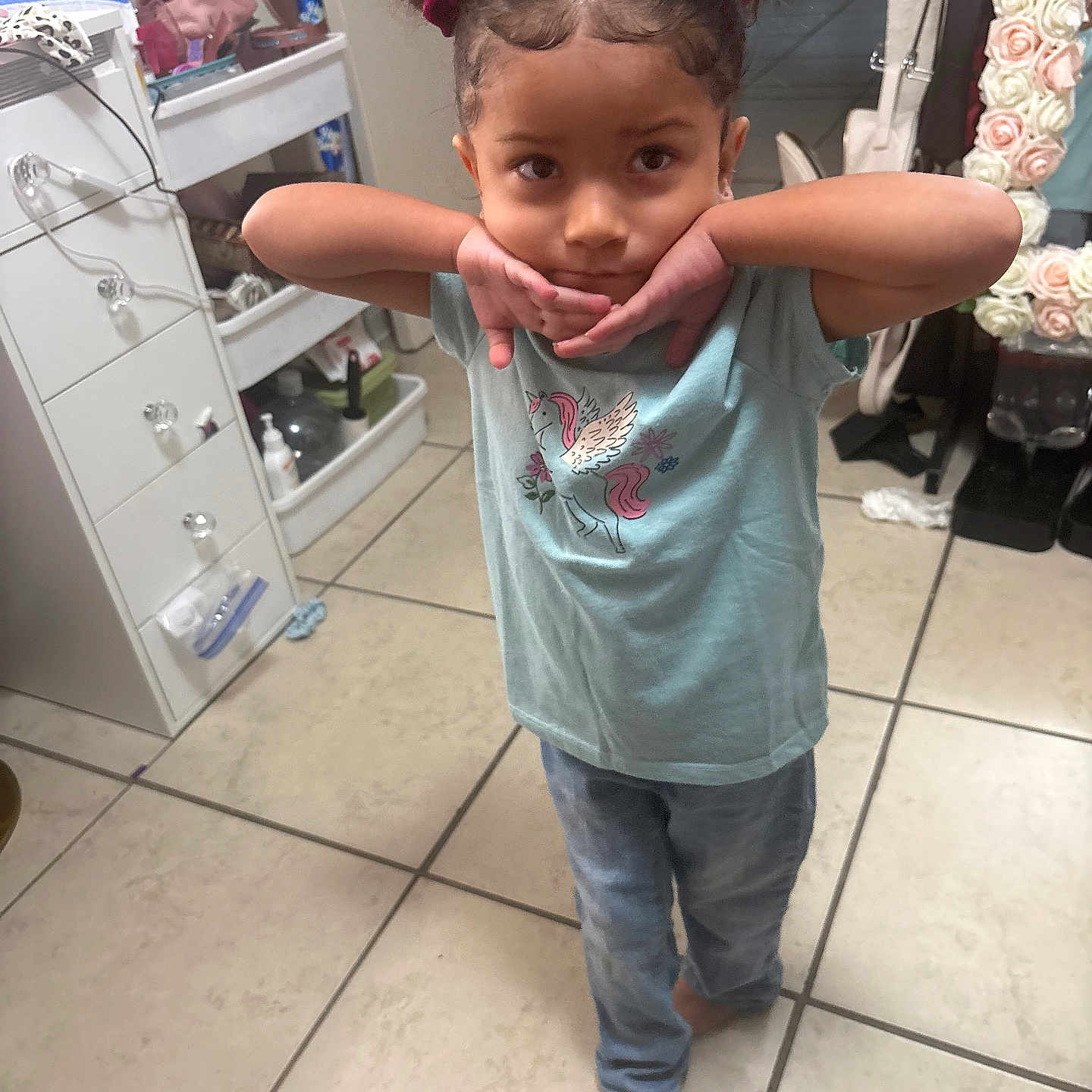 Sapphirerose joined the competition — help win amazing prizes! child, girl, portrait, indoors, bathroom, standing, smiling, pink_bows, hair_buns, unicorn_shirt, casual_clothing, jeans, barefoot, tile_floor, mirror, flowers, furniture, shelves, home, playful