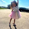 Sapphirerose is registered to the contest to win money with this photo: child, girl, toddler, portrait, smiling, curly_hair, dress, pink_skirt, tulle, outdoor, driveway, sunlight, blue_sky, clouds, long_shadow, parked_car, minivan, house, standing, playful