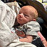 Derrick is registered to the contest to win money with this photo: baby, newborn, infant, person, human, portrait, clothing, fabric, hand, face, skin, head, table, controller, blanket, indoor, light, couch, sitting, holding