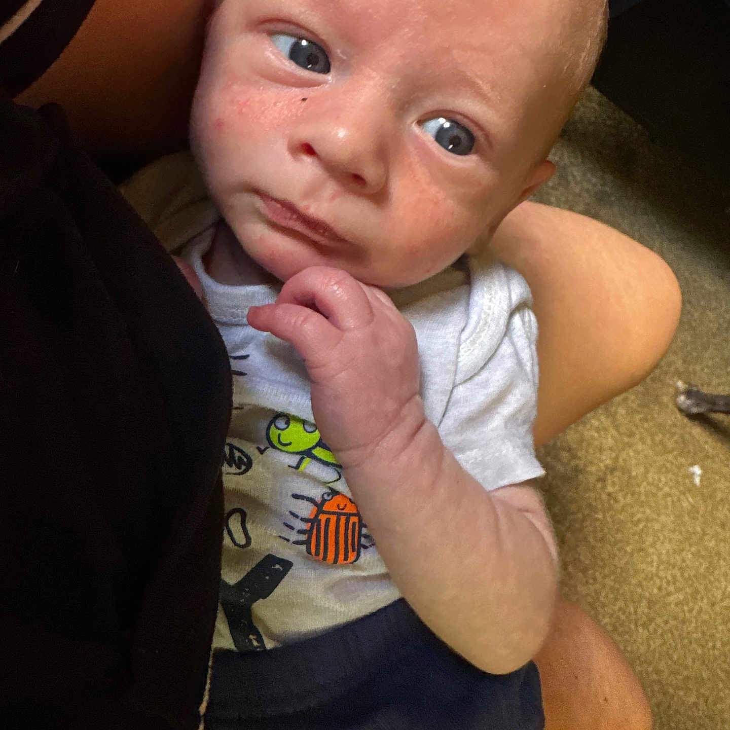 Derrick is registered to the contest to win money with this photo: baby, infant, child, person, face, hand, blue_eyes, clothing, shirt, cute, expression, indoor, carpet, human_skin, holding, seated, portrait, newborn, closeup, casual