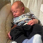 Derrick is registered to the contest to win money with this photo: newborn, baby, sleeping, infant, clothing, patterned, seat, cozy, hand, face, head, footwear, sock, soft, indoors, peaceful, cute, resting, child, portrait