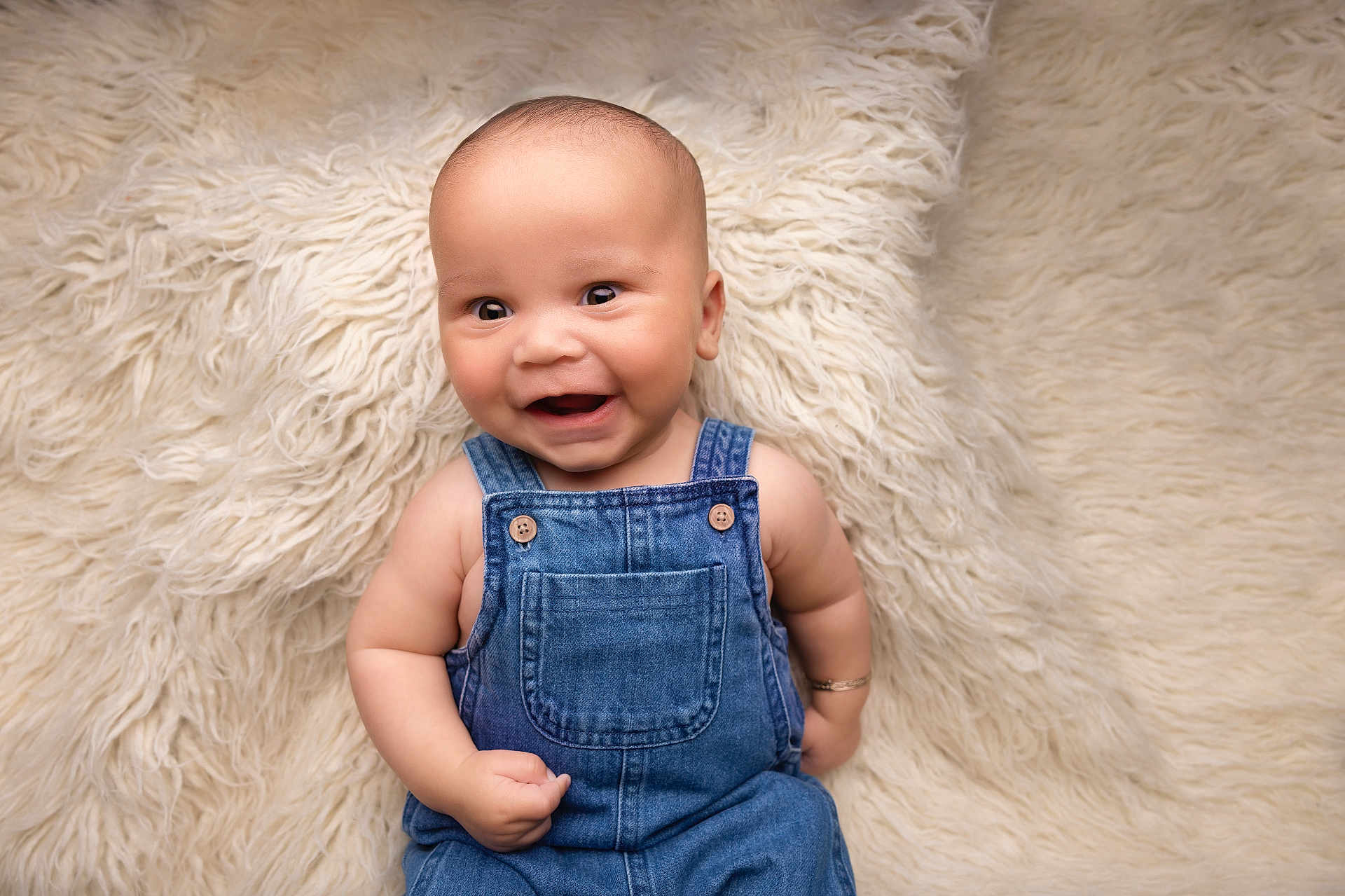 Roman is registered to the contest to win money with this photo: baby, denim_overalls, smile, happy, infant, cute, lying_down, fluffy_rug, texture, portrait, child, skin, cheerful, one_person, indoor, closeup, casual_clothing, baby_boy, young_child, expressive_face
