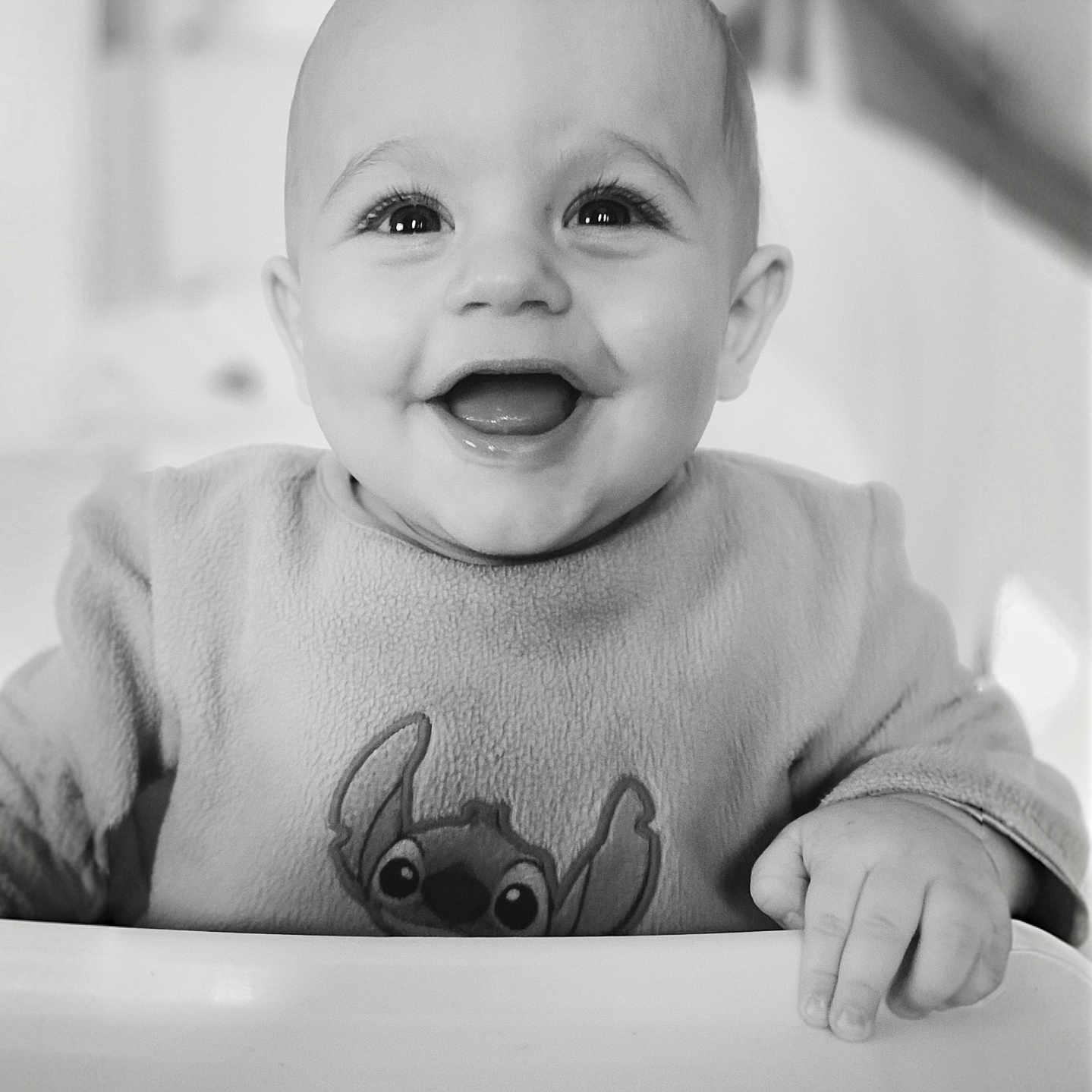 Ezio a rejoint le concours — aidez-le/la à gagner de superbes lots ! baby, black_and_white, cartoon_character, cheerful, child, closeup, clothing, cute, expressive_eyes, face, hand, happy, high_chair, indoors, infant, person, portrait, seated, smiling, sweater