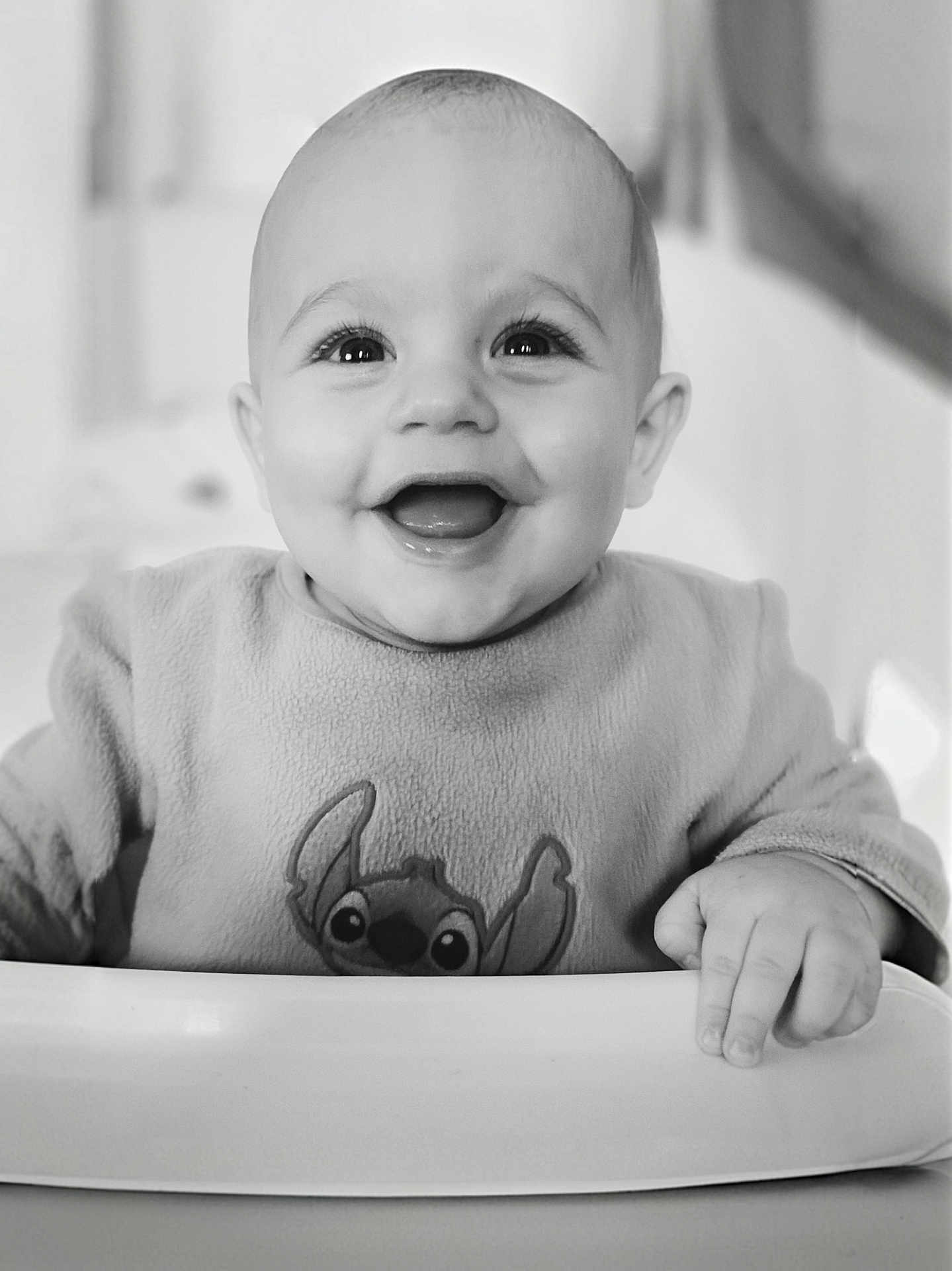 Ezio a rejoint le concours — aidez-le/la à gagner de superbes lots ! baby, smiling, happy, face, child, sweater, cartoon_character, high_chair, hand, portrait, indoors, black_and_white, cute, infant, expressive_eyes, cheerful, seated, clothing, person, closeup