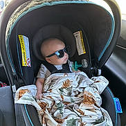 Braxlee is registered to the contest to win money with this photo: baby, car_seat, sunglasses, blanket, infant, car_interior, seat_belt, child, child_safety, seat, comfort, travel, shade, head_support, window, sunlight, relaxation, cute, protection, rest