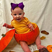 Katerina is registered to the contest to win money with this photo: baby, pumpkin, purple_bow, smiling, autumn_leaves, orange, yellow_shirt, cute, infant, fall, holiday, costume, playful, sitting, white_background, happy, child, seasonal, portrait, fun