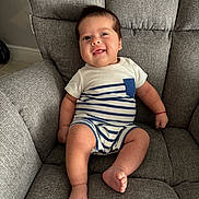 Jordan is registered to the contest to win money with this photo: baby, child, smiling, onesie, striped_clothing, armchair, gray_fabric, indoors, happy, cute, infant, sitting, portrait, cozy, furniture, skin, face, foot, hand, red_bracelet