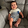 baby, child, smiling, onesie, striped_clothing, armchair, gray_fabric, indoors, happy, cute, infant, sitting, portrait, cozy, furniture, skin, face, foot, hand, red_bracelet