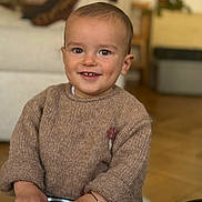 Léon a rejoint le concours — aidez-le/la à gagner de superbes lots ! baby, background, bracelet, child, cozy, cute, face, furniture, hands, happy, indoor, knitwear, metal, person, portrait, smile, sweater, toddler, wood_floor, young_child