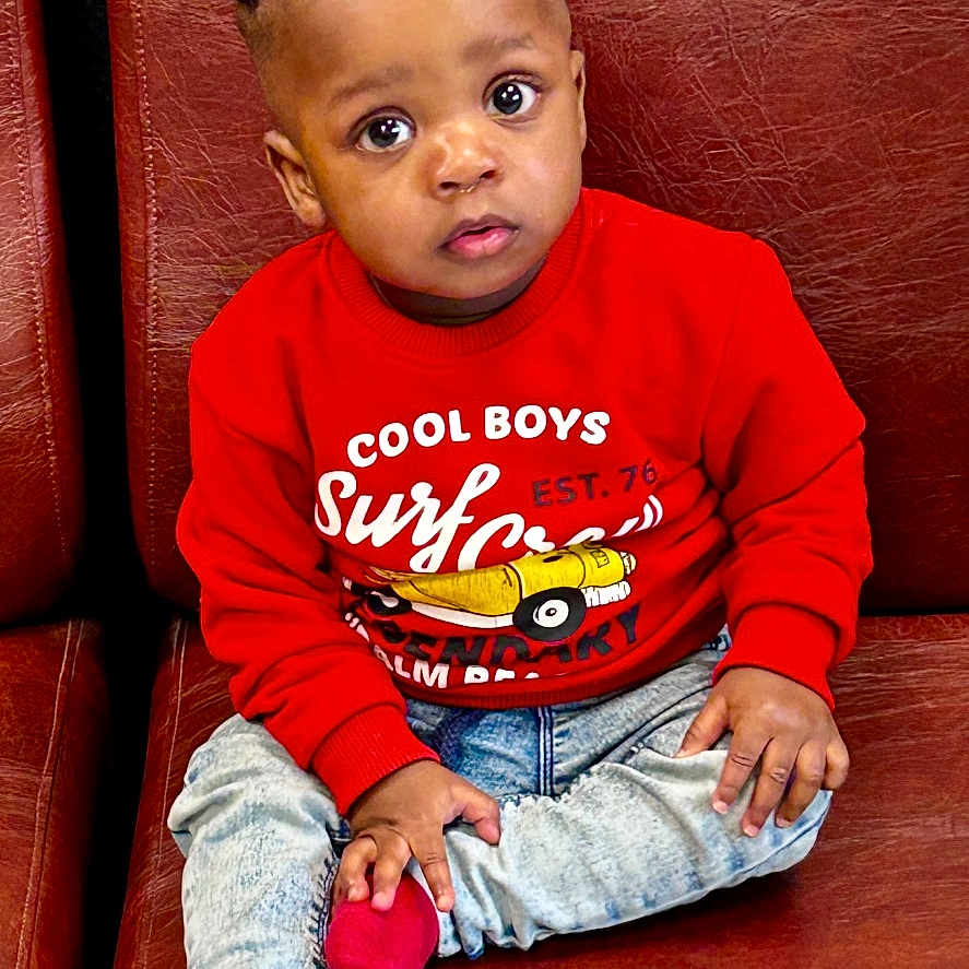 Aboubakar Khalil participe au concours pour gagner de l'argent avec cette photo : boy, casual_clothing, child, curly_hair, cute, expression, face, fashion, home, indoors, jeans, leather_couch, person, portrait, red_socks, red_sweater, seated, sitting, toddler, young_child